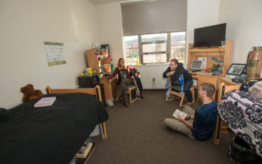 Three students hang out in residence hall room