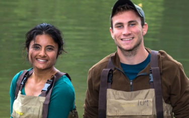Two students in waders smile at the camera