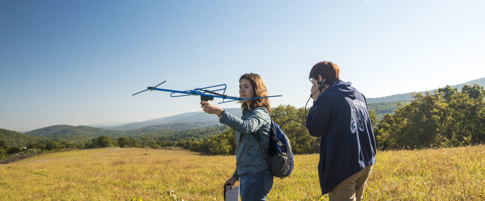 Two students hold telemetry equipment in a field